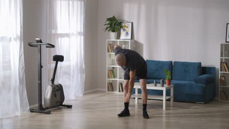 middle-aged-man-is-doing-gymnastics-at-home-at-morning-at-weekend-warming-muscles-and-joints-exercises-for-health-of-body